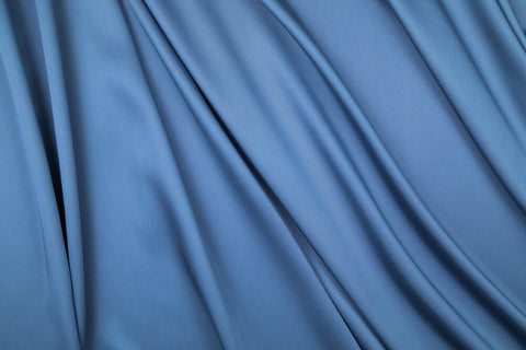 A sateen cut of blue fabric, spread out by soft draped folds.