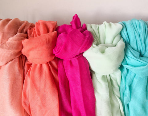 Plain multi-coloured ladies' viscose scarves aligned on a clothes rack.