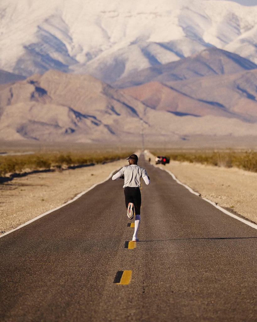 Runner running on paved road towards a brown mountain background