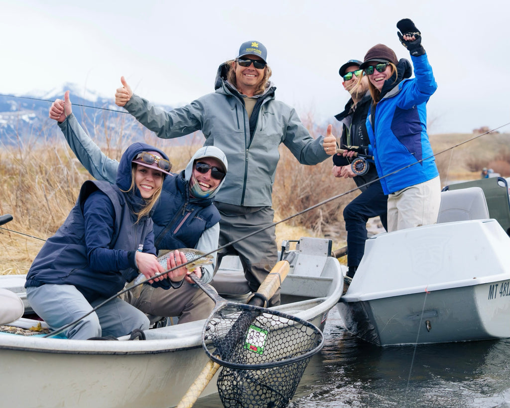 Group of five people on a boat, with one holding a fish