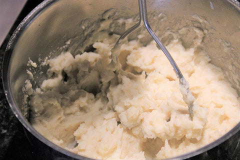 mashing potatoes in a pot