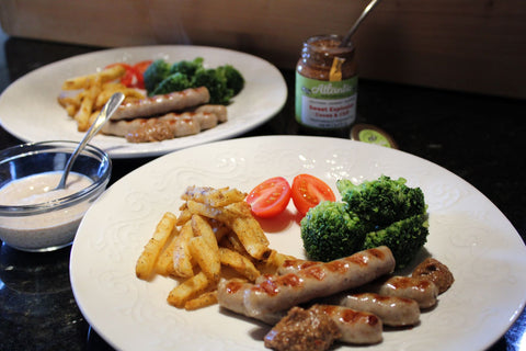 Two plates with sausages, vegetables, fries and mustard