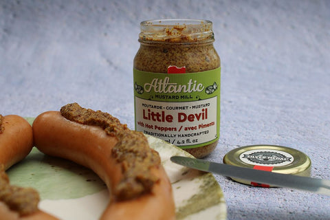 A plate with a pair of wieners and a Little Devil mustard jar