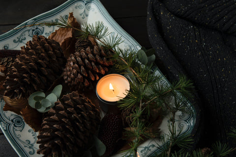 pine cones and lit candle holiday self care