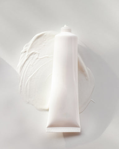 Tube of skincare laying on cream