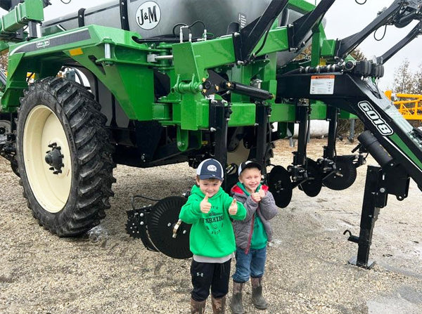 2 boys giving a thumbs up while standing in front of a new 6018 Liquid Applicator