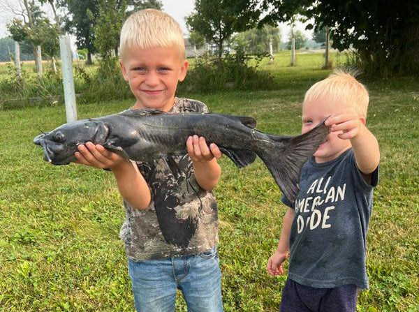 2 young boys holding a fish