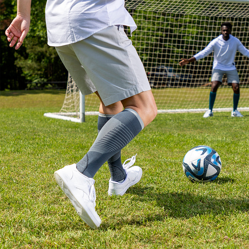 Sigvaris Motion Flow Tech soccer Man kicking a soccer ball, wearing Motion Flow Tech in the color Slate