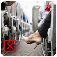 View of an airplane aisle; a woman wearing heels has her foot sticking out from the seat