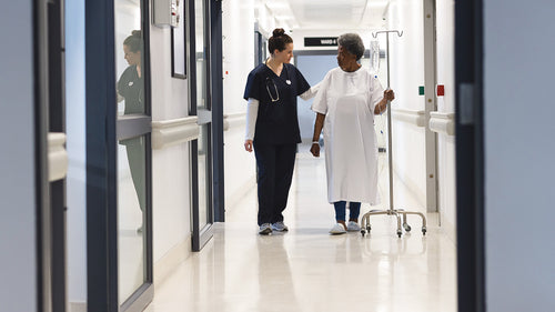 nurse walking with a patient in hospital corridor