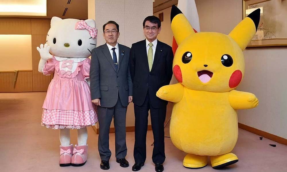 2 men surrounding by Japanese-kawaii-culture with Hello Kitty mascot on the left, and pokemon Picachu on the right