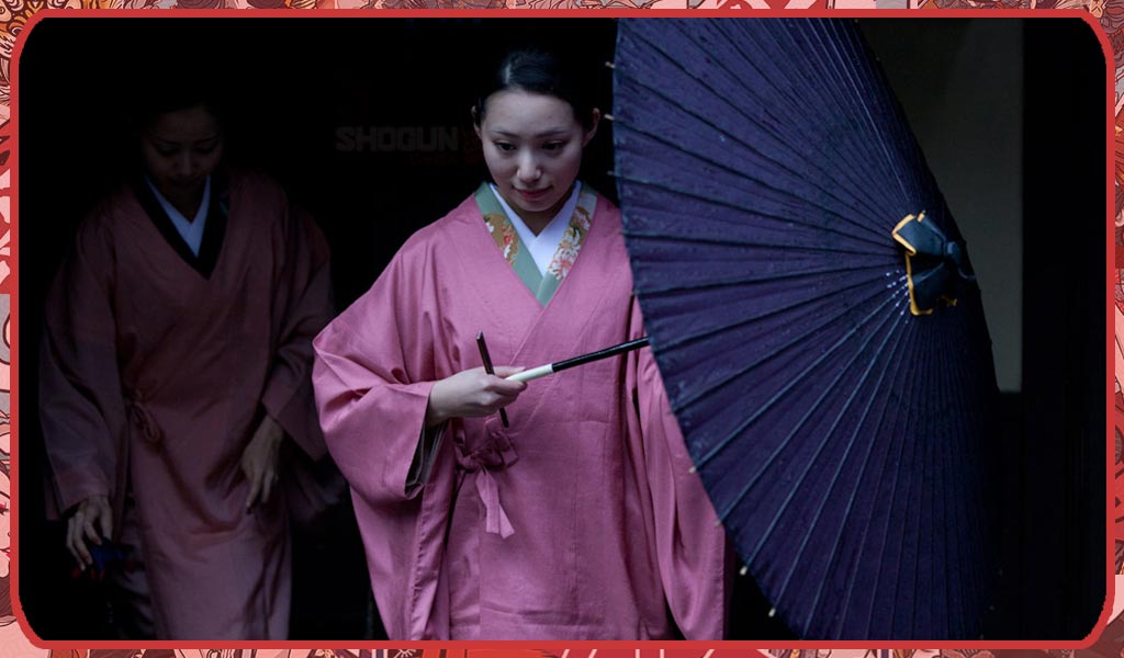 A woman wears a traditional Japanese Dochugi coat and an umbrella