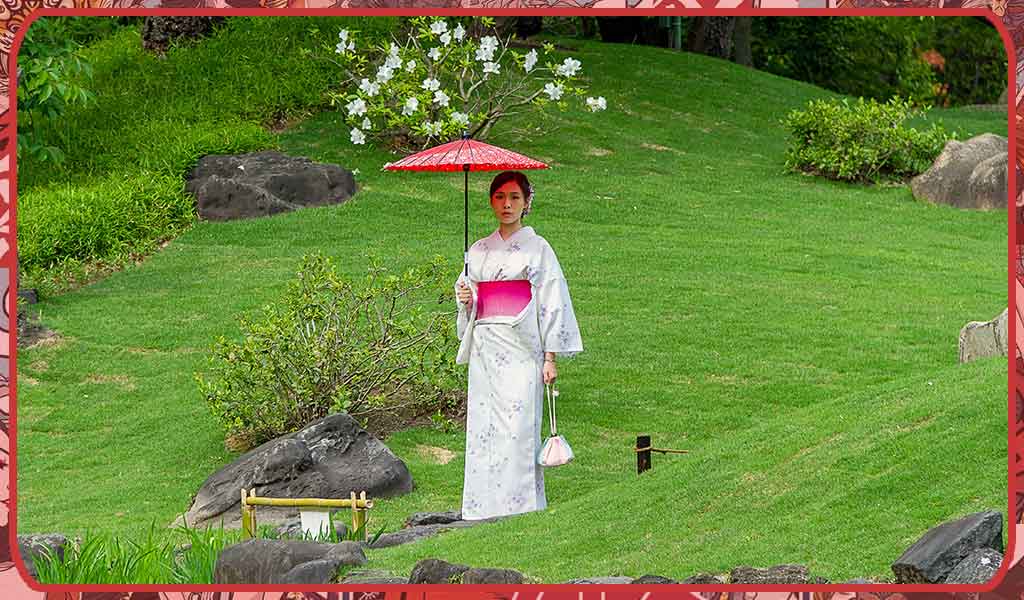 A woman wears a Japanese silk kimono in a park in Okinawa