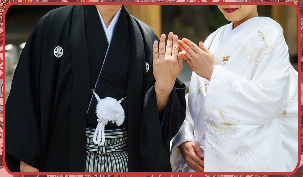 A men wearing a black wedding kimono, a hakama and a haori jacket. A woman wearing a white kimono