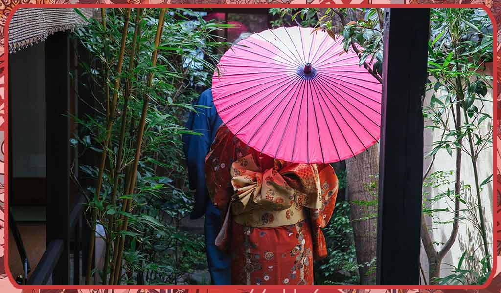 Traditional kimono Japan wearing by a man and a woman walking in kimono in a garden with an umbrella