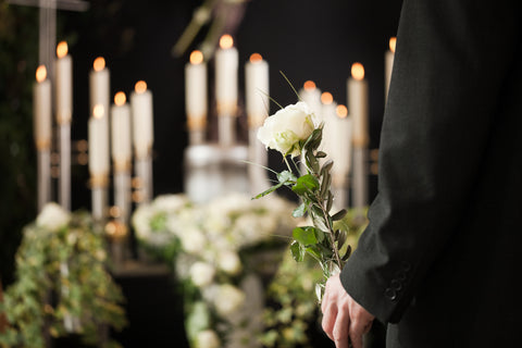 man in front of funeral flower arrangement