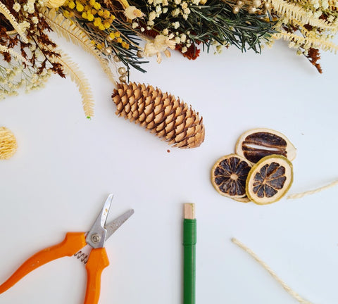 Werkmateriaal om zelf een kerstguirlande te maken: touw, ijzerdraad, droogbloemen en een kniptang