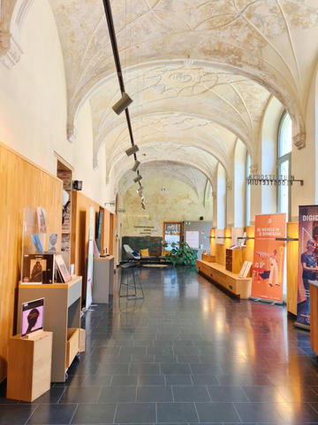 Wandelgang van de vernieuwde bilbiotheek in Mechelen met oude gewelven en een knusse leeshoek