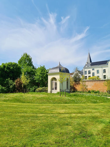 Grasveld van de stiltetuin in Mechelen met een boswachtershuis in het midden en statige woningen op de achtergrond