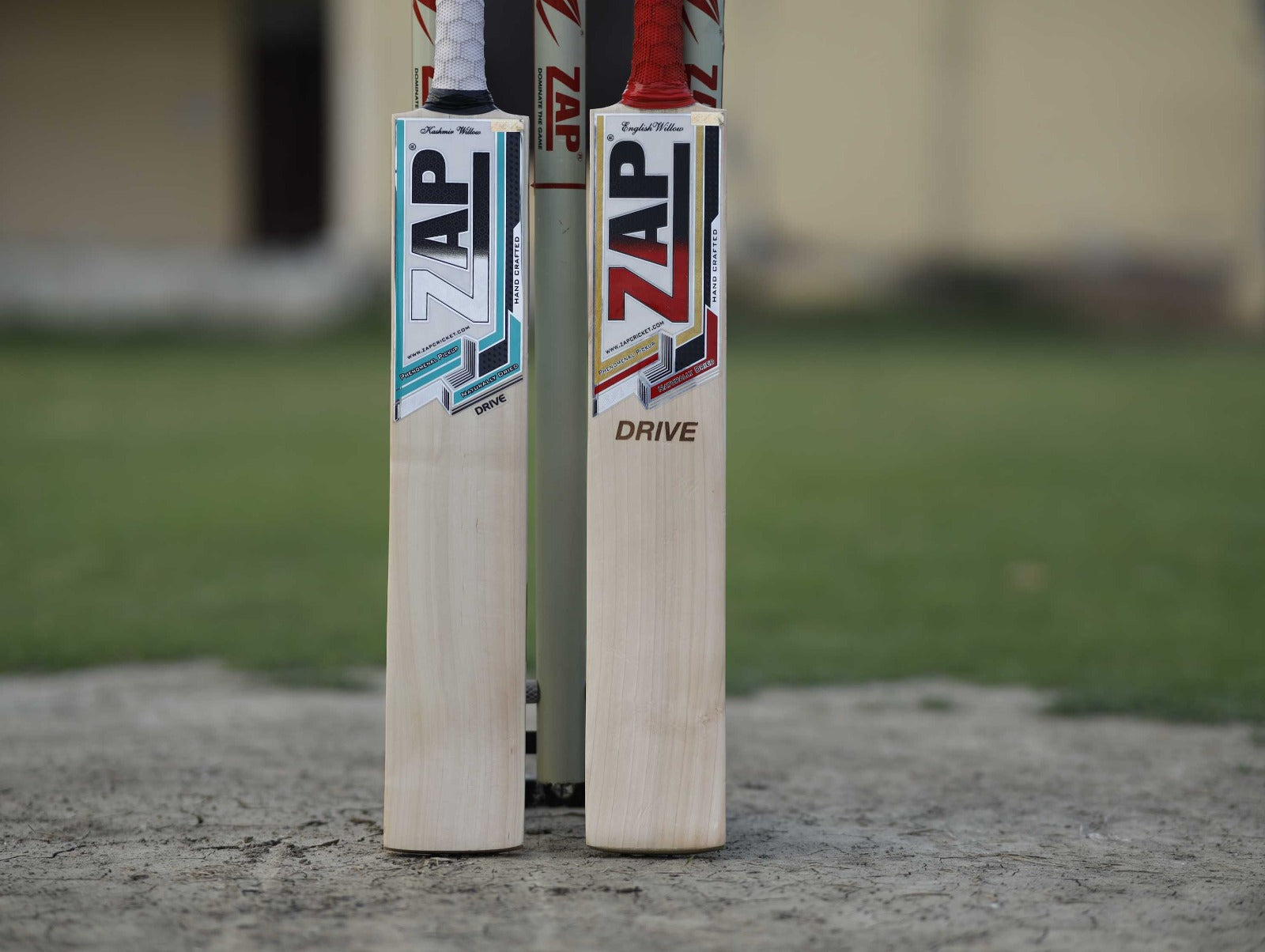 ZAP Kashmir Willow Cricket Bat and English Willow Cricket bat placed beside each other with the stumps as a Support