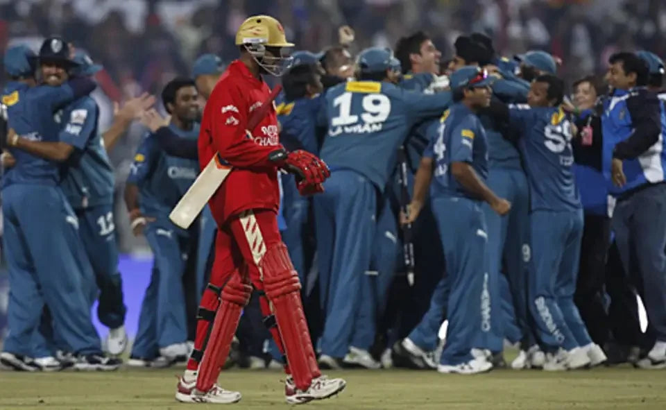 An RCB Batsman passes past the Deccan Chargers players celebrating the wicket in the background