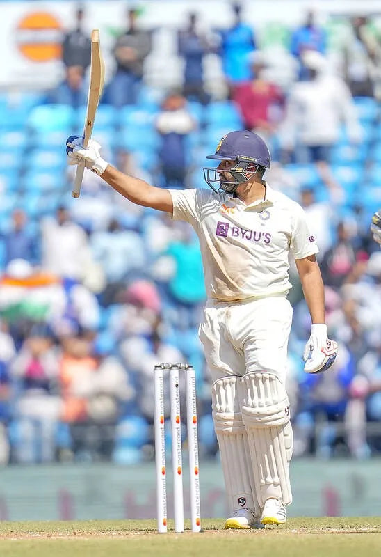 Rohit Sharma raises his bat to celebrate a half century in a test match