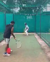 A player bats against the tennis racked drill in the nets with his cricket coach
