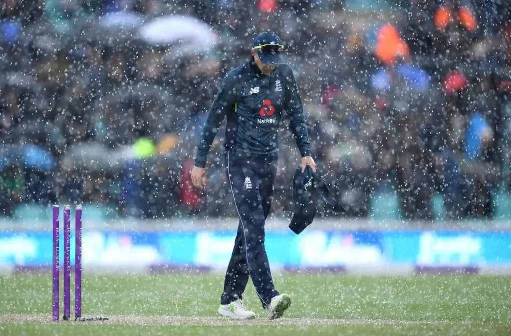 Joe Root walks through rain pouring down during a cricket match