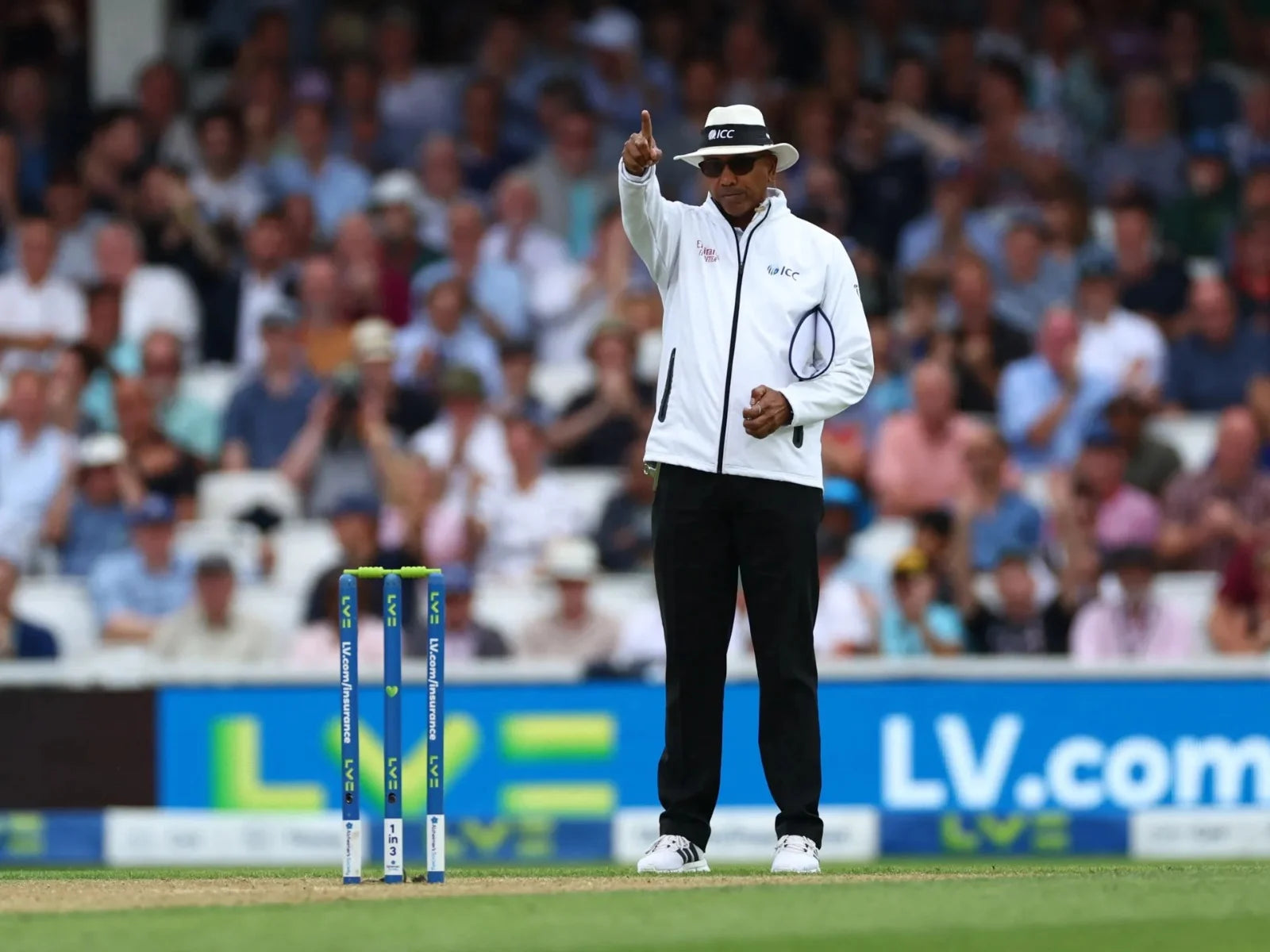 A cricket umpire raising his finger to declare the decision out!