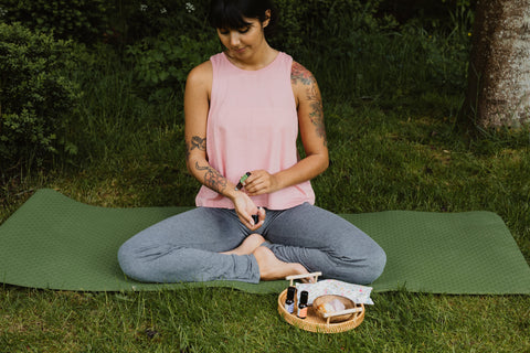 woman applying aromatherapy oil to wrist when meditating outside 