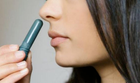 woman inhaling from aromatherapy essential oil inhaler stick