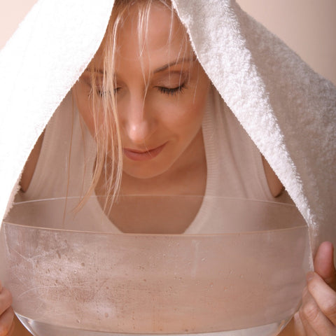 woman inhaling from bowl with essential oils