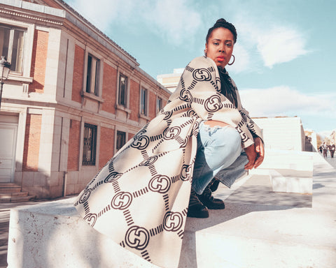 POC Black Woman in a gucci cape knelling in front of the Prado museum.  Editorial  Photography in Madrid.  Madrid Model. Female Model in the sunlight. Natural Light Portrait of a black woman. www.aaronjeanphotography.com