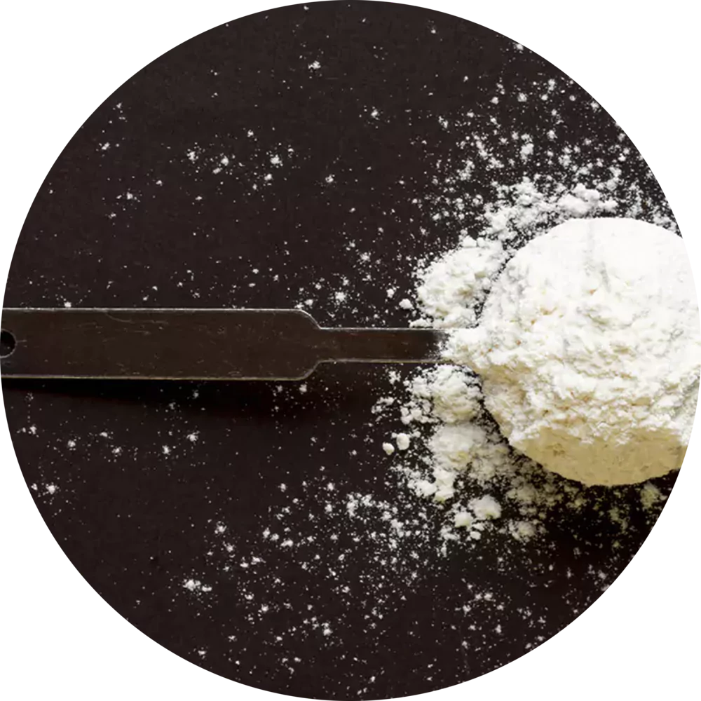Measuring spoon filled with flour on a black surface.