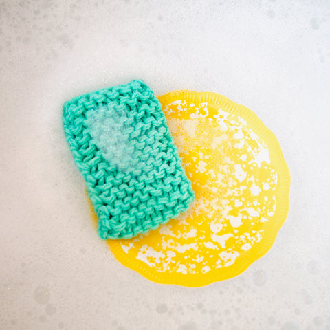 Green Cotton Forever Sponge in a sink of bubbly water with yellow speckled dish.