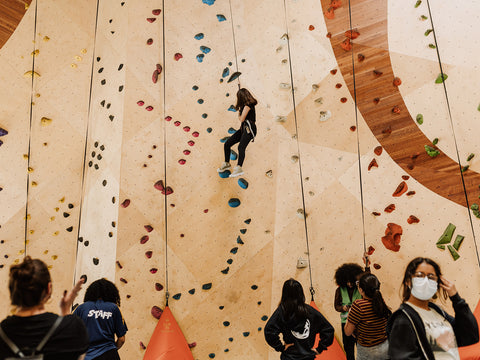 Tru Flask Adventure Club participant scales an indoor rock climbing wall.