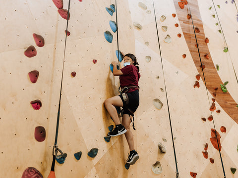 Young girl climbs an indoor rock wall
