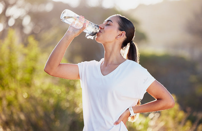 A woman on the trail drinking water from a bottle