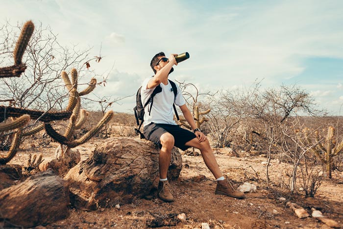 A hiker in a desert drinking from a bottle