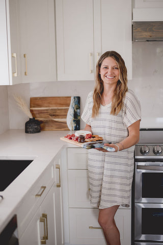 woman holding a medium resin cheeseboard in white kitchen