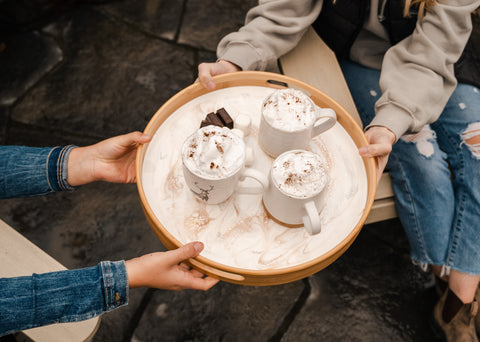 friends enjoying hot chocolate over a bonfire, served on a resin tray