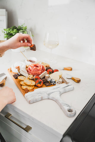 woman placing chocolate covered strawberries on a resin accented cheese board for valentines day