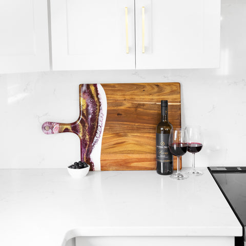 merlot design resin accented cheese board leaned against the countertop wall in white kitchen