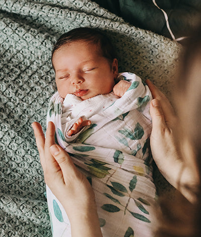 By swaddling baby, it restricts your baby's arms and legs from jerking, mimics the tight confines of the womb, and prevents SIDS.