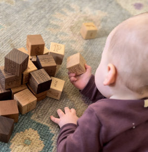 child holding M block in set of abc blocks