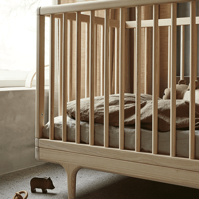 detailed image of oiled ash caravan crib in the bedroom with mattress and toys on the crib and floor -- Lifestyle