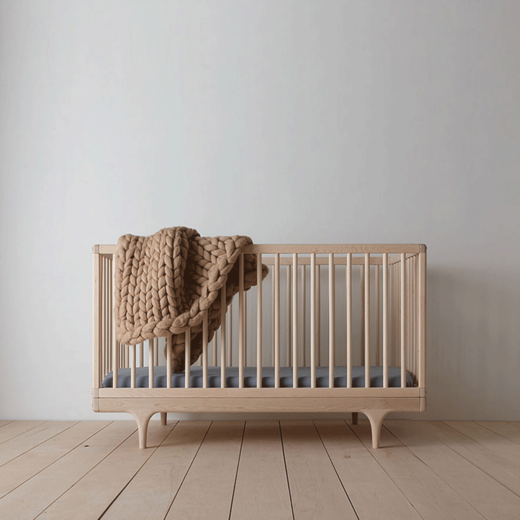 the front view of oiled ash caravan crib with mattress and blanket on side wall -- Lifestyle