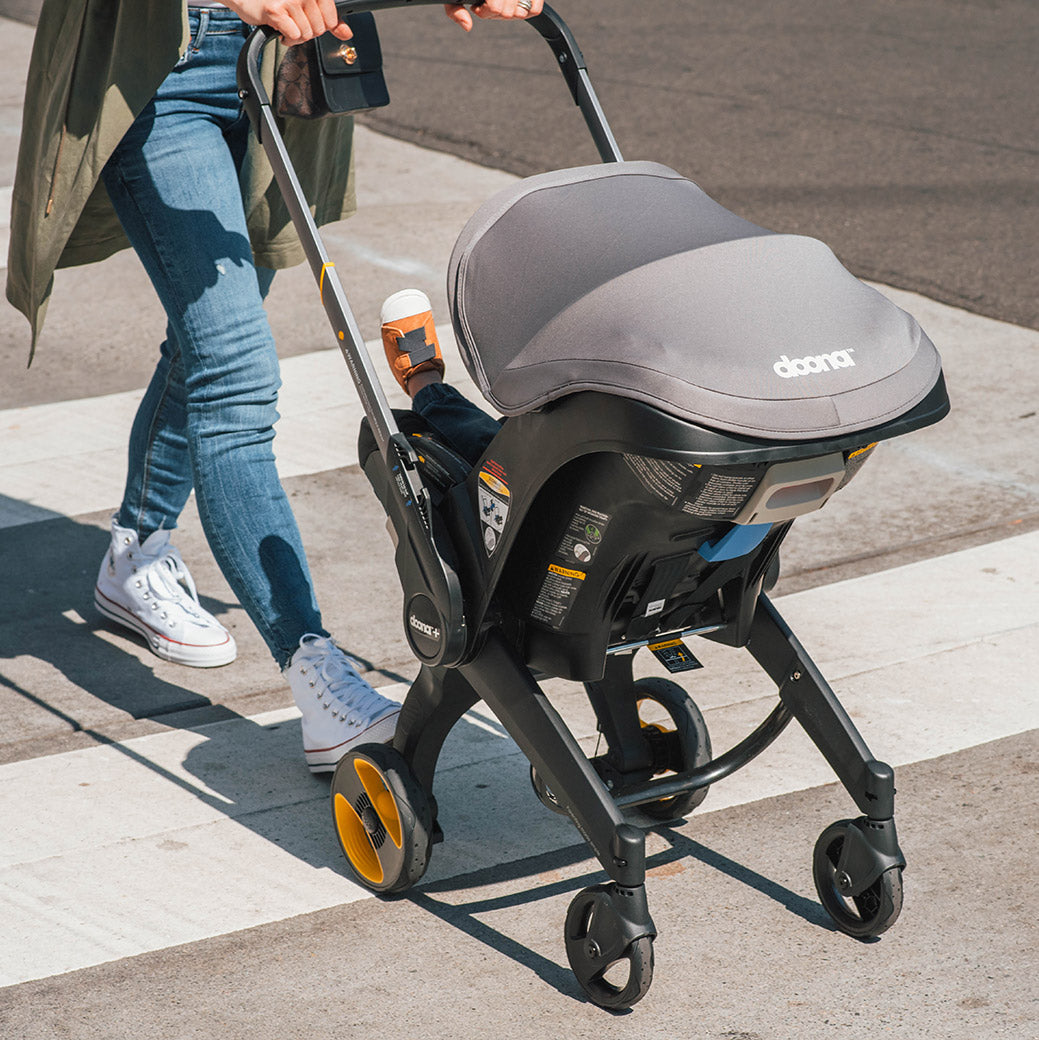 Front view of Doona Infant Car Seat and Stroller in Grey Hound on the sidewalk -- Color_Greyhound