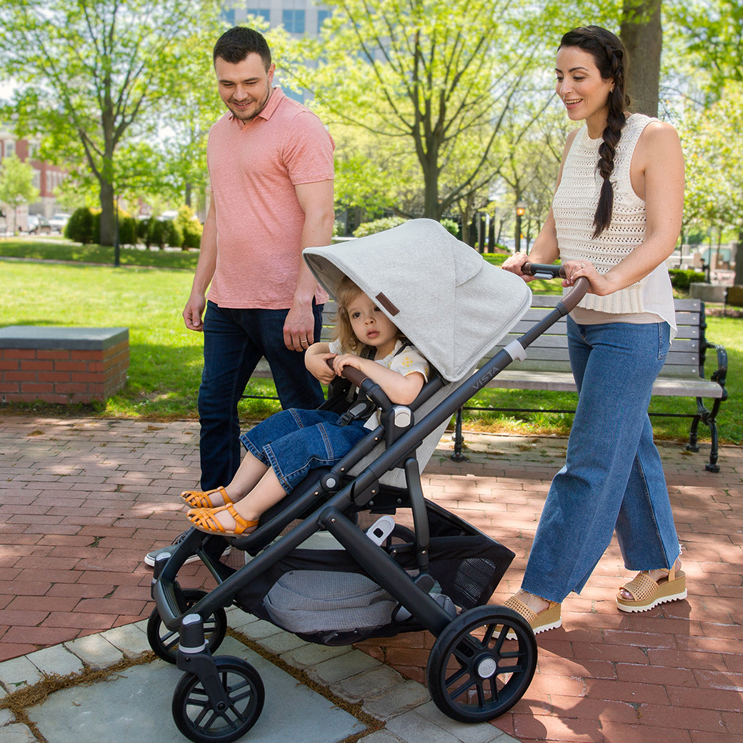 Woman pushing the vista v2 stroller in Anthony while man looking at the child in the stroller -- Color_Anthony