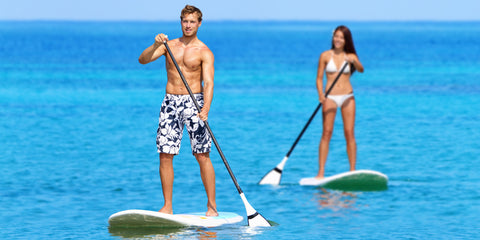 Man and woman paddle boarding in the summer
